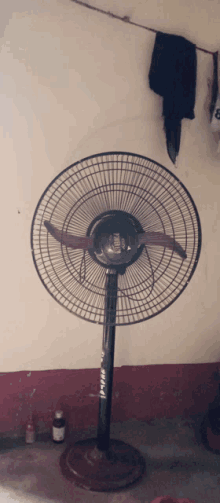 a fan that says ' which ' on it sits in front of a wall