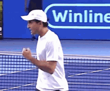 a man wearing a white hat and a white shirt stands on a tennis court in front of a sign that says winline