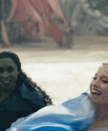 a woman in a blue dress is laughing with another woman .