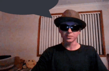 a man wearing a hat and sunglasses looks at the camera