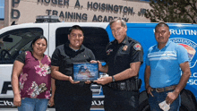 a group of people standing in front of a roger a. hoisington training academy van