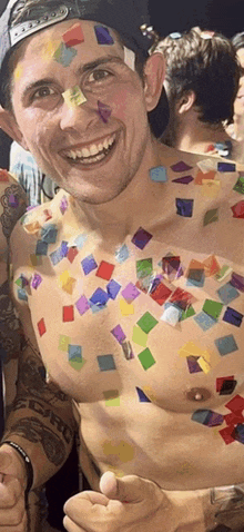 a shirtless man with confetti on his chest has a tattoo on his arm that says aero