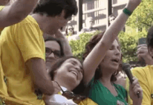 a woman in a green shirt is singing into a microphone in front of a crowd of people wearing yellow shirts