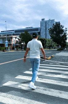 a man in a white shirt and a black hat is crossing a street