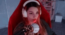 a woman wearing headphones and a mask is sitting in a red chair .