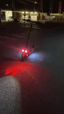 a scooter is parked on the street at night with red lights