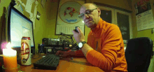 a man sitting at a desk with a can of osman beer