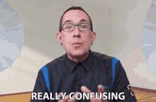 a man with glasses says really confusing in front of a white wall