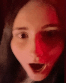 a woman with red paint on her face is making a surprised face .