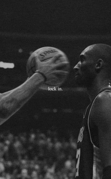a black and white photo of a man holding a basketball with the words lock in below him