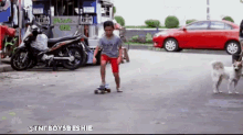 a young boy is riding a skateboard down a street with a red car in the background and a sign that says private use