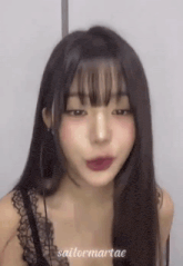 a close up of a woman with long hair and bangs wearing a black lace bra .