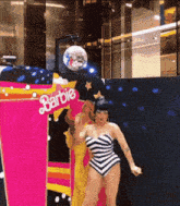 a woman is dancing in front of a barbie display