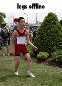 a man in a red and white leotard is standing in the grass with the words legs offline below him .