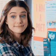 a girl is smiling in front of a sign that says i am a poet