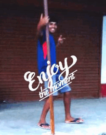 a man is standing next to a pole with the words enjoy the moment written on it