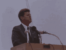 a man in a suit and tie is speaking into a microphone