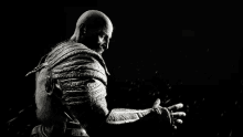 a black and white photo of a bald man with a beard standing in the dark with his arms outstretched .