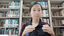 a woman in a black shirt with a nasa logo on it is standing in front of a bookshelf in a library