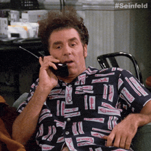 a man is talking on a cell phone with the hashtag #seinfeld on the bottom