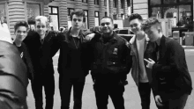 a group of young men are posing for a picture with a police officer in a black and white photo