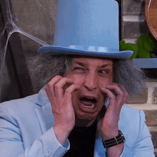 a man wearing a top hat and a blue suit making a funny face