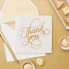 a thank you card is sitting on a table next to a pen