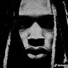 a black and white photo of a man with dreadlocks on his head .