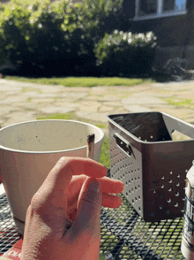 a person smoking a cigarette on a table with a bowl in the background