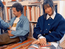 a man and a woman are sitting in front of a bookshelf with a book titled the taste of the rainbow on it .