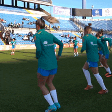 a group of female soccer players are on a field and one of them is wearing a green neoenergy shirt