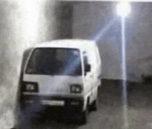 a white van is driving down a street in a dark room .