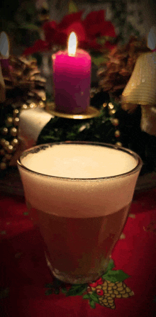 a purple candle is lit in a candle holder next to a glass of liquid