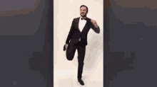 a man in a tuxedo and bow tie is dancing with the name camille on the bottom .