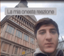 a young man stands in front of a building with the words la mia onesta reazione above him