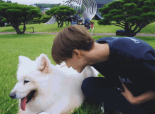 a man kneeling down next to a white dog wearing a black shirt that says ' duke ' on it