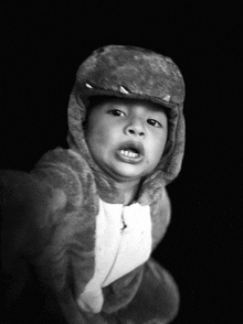 a black and white photo of a child wearing a dinosaur outfit