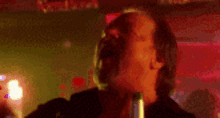 a man is singing into a microphone in a dark room in a club .