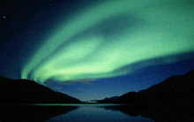 the aurora borealis is visible over a lake