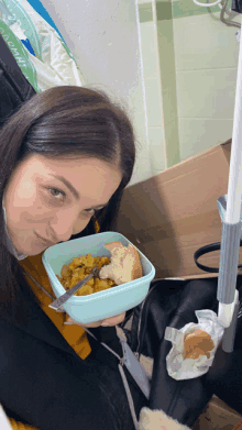 a woman is holding a bowl of food with a spoon in her hand