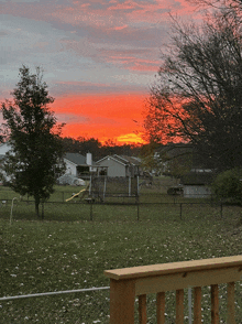 a sunset over a residential area with a wooden railing