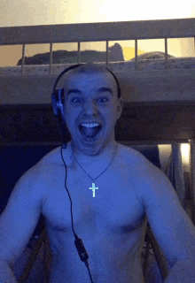 a shirtless man wearing headphones and a cross necklace is making a funny face