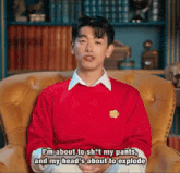 a man in a red sweater is sitting in a chair and saying i 'm about to sh * t my pants