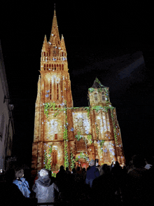 a group of people standing in front of a large building that is lit up