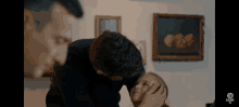 a man kisses a little girl on the forehead in front of a painting that says adore