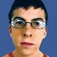 a close up of a young man wearing glasses and a red tank top .