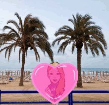 a pink heart with a cartoon girl on it in front of a beach