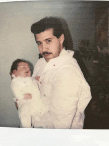 a man in a white shirt holds a baby