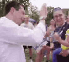 a man in a white shirt is giving a high five to a woman in a crowd of people .