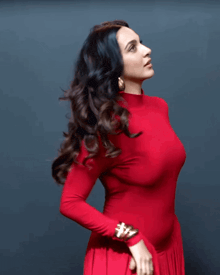 a woman wearing a red turtleneck and gold earrings